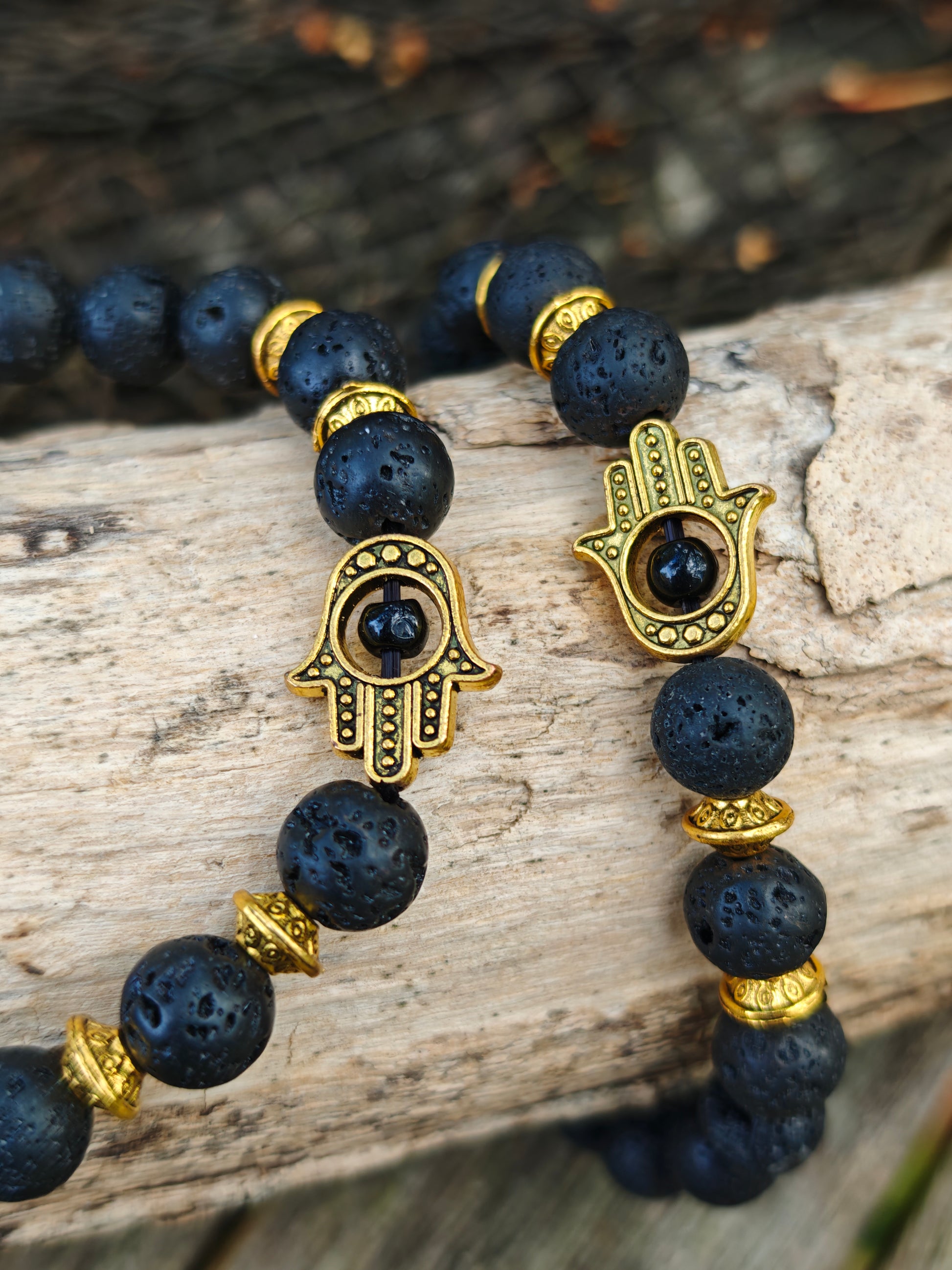 Armband mit Lava-Stein und goldenen Hamsa-Anhänger